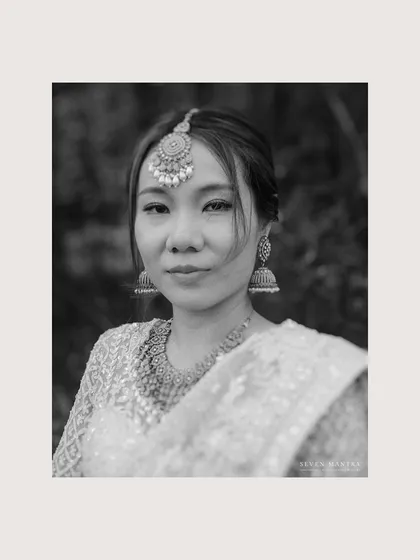 A timeless black and white portrait. Stripping away the color allows the bride's expression and the traditional details of her maang tikka and jhumkas to take center stage, creating a soulful and classic image.