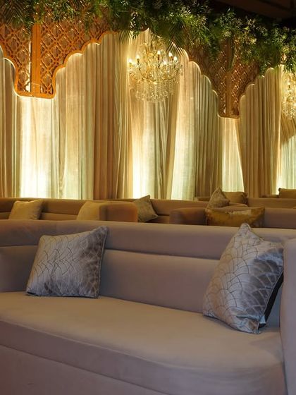 A comfortable and chic seating deck with modern sofas, elegant drapes, and chandeliers, designed for guests to enjoy the celebration in style.