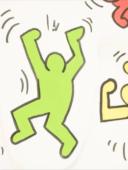 A close-up of a green figure from the "Dripping Pop" installation, showcasing the clean lines and bold colors inspired by Keith Haring.