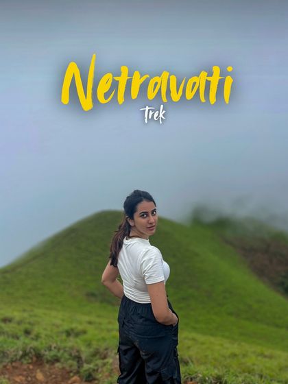 A solo trekker looking back with a smile, with the Netravathi trail stretching out behind her.