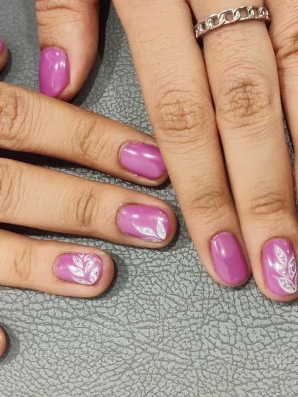 A simple white leaf design on a pretty lilac base. This shows how a small artistic touch can elevate a solid color manicure.