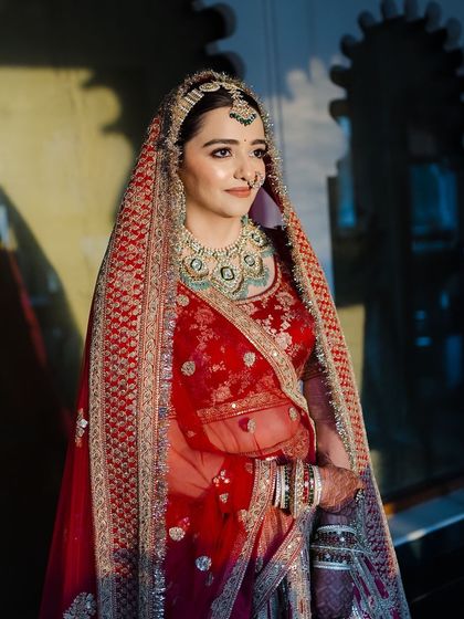The bride bathed in a soft light, highlighting the intricate details of her outfit and the subtle glow of her makeup.