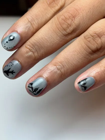 A side view of the travel-inspired nail art, focusing on the airplane and location marker. It’s these small, personalized details that make a set truly unique.