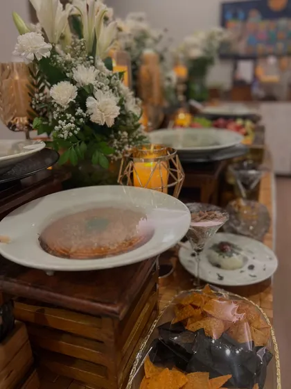 An evening grazing table set under ambient candlelight. The spread includes our signature dips, artisan cheeses, and a variety of crackers, all beautifully integrated with floral and candle decor.