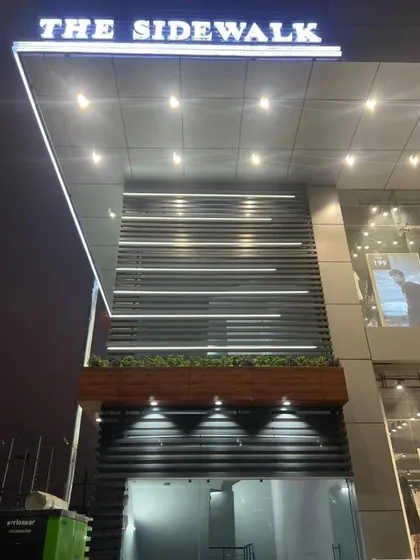 A closer look at the entrance of 'The Sidewalk'. I designed the facade with a combination of dark louvers, a wooden planter box, and bright overhead lighting to create a well-defined and attractive entry point.