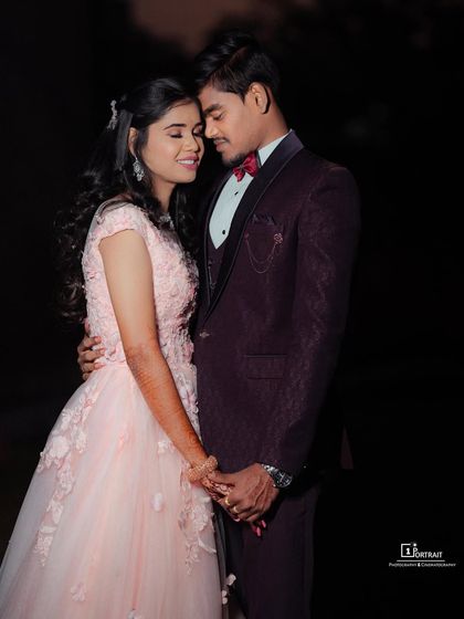 A fairytale engagement look. The soft pink gown with delicate floral details complements the groom's sharp wine-colored suit, creating a perfectly coordinated couple's outfit.