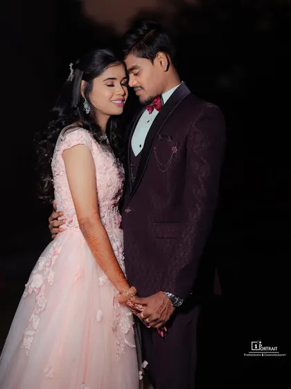 A fairytale engagement look. The soft pink gown with delicate floral details complements the groom's sharp wine-colored suit, creating a perfectly coordinated couple's outfit.
