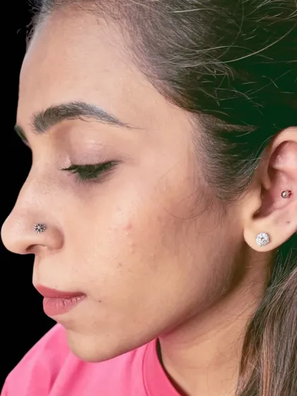 A clean and classic look with a nostril stud and a cartilage hoop. I take care to get the placement just right for both aesthetics and proper healing. This shows my expertise in delicate facial and ear piercings.