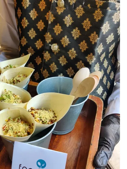 A server presenting street food-inspired snacks in eco-friendly paper cones. We love to add a fun, interactive element to our menus, and this creative take on bhel puri was a hit at a private brunch.