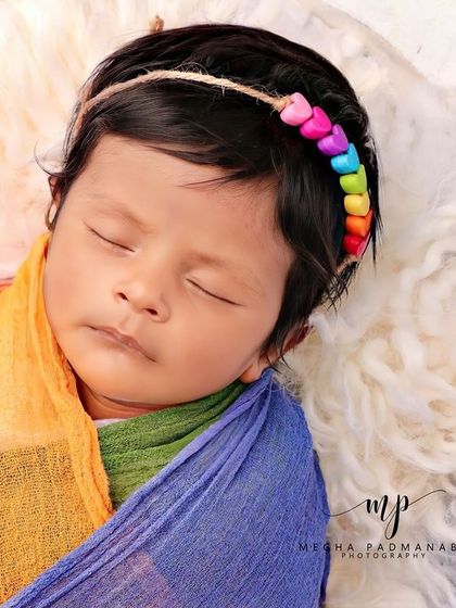 A close-up of the baby's face and their colorful beaded headband.