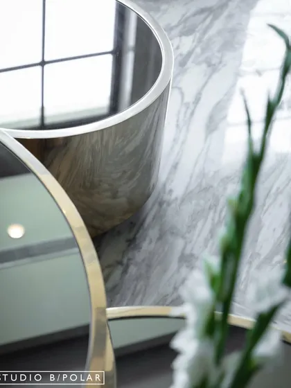 A detail shot showing the reflection in the mirrored coffee table, capturing the light and the elegant lines of the furniture. It’s these small moments that contribute to the overall sense of luxury.