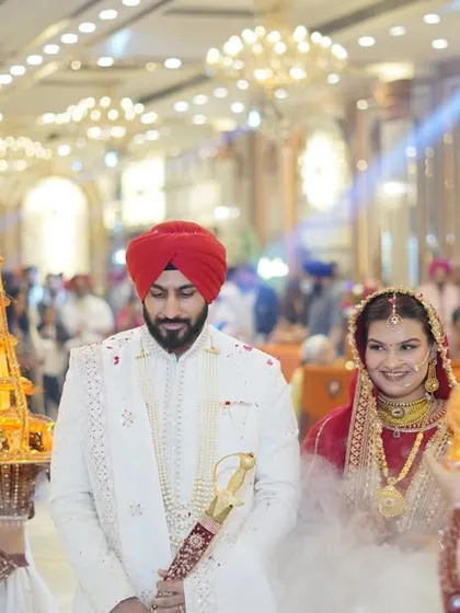 A royal entrance for the couple, flanked by attendants carrying decorative lights. This wide shot captures the grandeur of the moment.