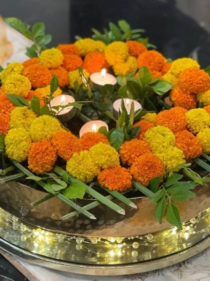 Another angle of the marigold urli, showing the lit candles nestled among the flowers. This combination of candlelight and floral beauty is a simple way to create a serene and joyful atmosphere.