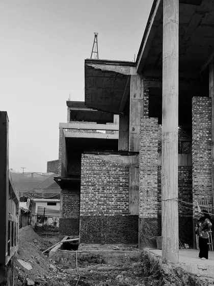 The side elevation of a building under construction, showing the exposed brick and concrete pillar framework.
