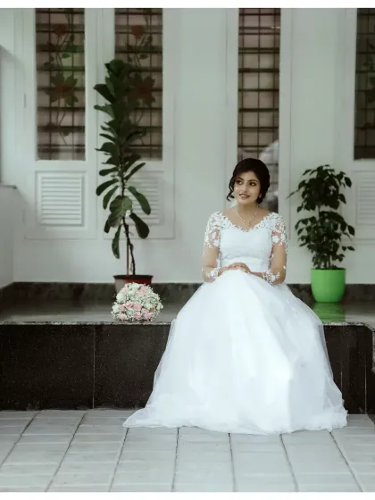 The bride seated, her gown elegantly spread around her. This serene portrait captures a moment of quiet contemplation before the festivities.