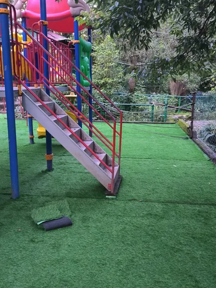 During the installation process at the Nainital Eco Cave Garden. The grass rolls are cut to fit perfectly around the play equipment.