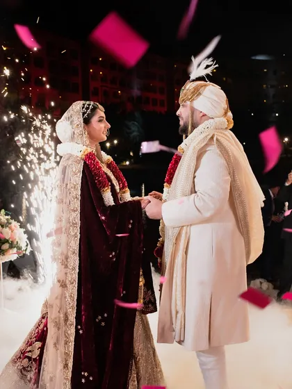 A tender moment as the groom bows for the varmala, with a backdrop of fireworks and a cascade of red confetti. We capture the emotion and grandeur of traditional ceremonies.