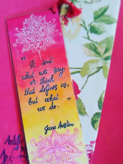 I create custom bookmarks with your favourite quotes, like this one featuring a Jane Austen line. It's painted with a warm watercolour gradient and detailed with a white lotus mandala, and it comes with a protective cover and tassel.