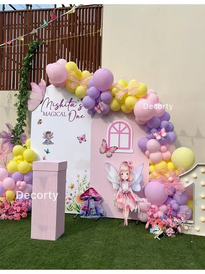 Welcome to Mishita's "Magical One" fairy-themed party. This beautiful backdrop features a fairy house, pastel balloons, floral details, and a light-up number one.