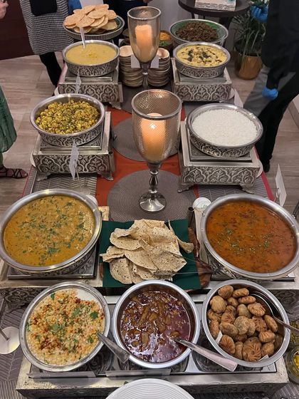 An overhead view of a traditional Indian winter feast, with a variety of dals, curries, and breads served in beautiful silverware.