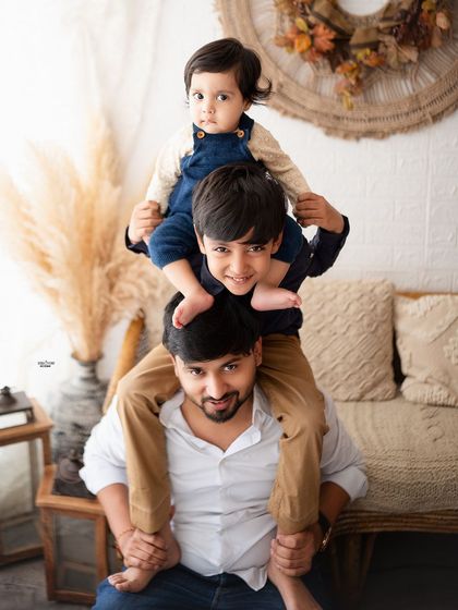 A fun and playful shot of a father with his two sons, one riding on his shoulders.