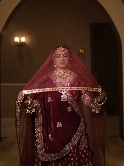 A candid moment of the bride adjusting her veil. The soft lighting beautifully captures the details of her airbrush makeup and intricate jewellery.