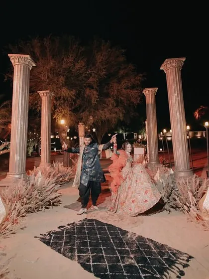 The couple's grand entrance to their 'Night on the Nile' Sangeet, set against a backdrop of towering pillars in the desert.