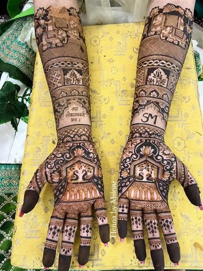 A personalized bridal mehendi for a Jain bride. The design includes her and her partner's initials, "SM," and a religious verse, "Sarva Mangal Mangalye."