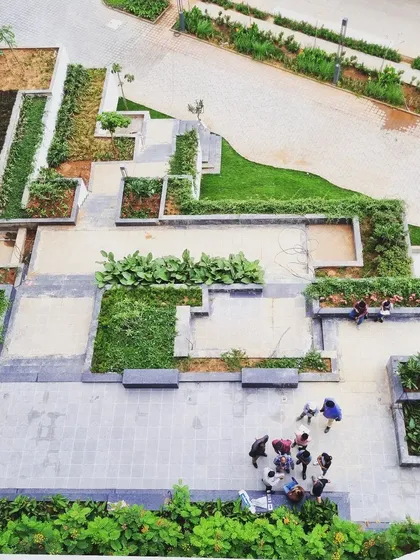 An overhead view of a podium landscape nearing completion. The geometric layout of planters, pathways, and seating areas creates a structured yet inviting communal space for residents to enjoy.