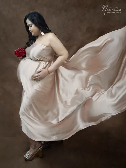 An artistic shot that uses the flowing fabric to create a sense of movement and grace. The side profile beautifully highlights her baby bump.