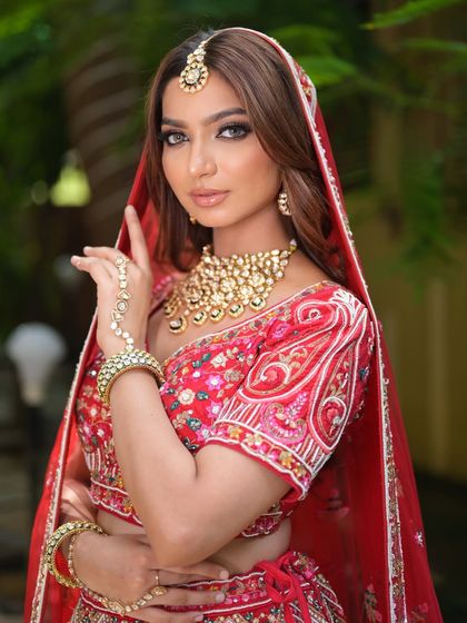 The quintessential bridal pose. This rental look features a classic red lehenga and a full kundan jewellery set, perfect for your wedding album.