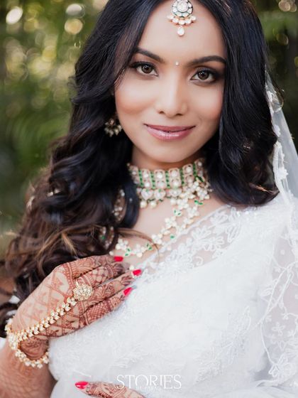 An elegant bride dressed in a beautiful white lace saree. Her traditional jewelry and intricate mehendi provide a stunning contrast, creating a portrait of grace and modern sophistication.