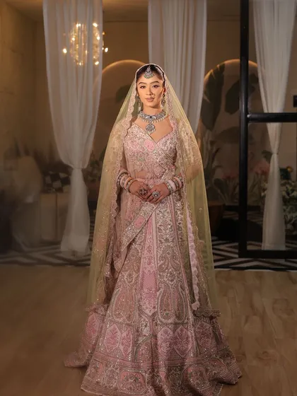 A full-length view of this stunning pink zardozi bridal lehenga. The double dupatta styling adds a touch of royalty, and the intricate paisley motifs are a nod to our rich heritage.