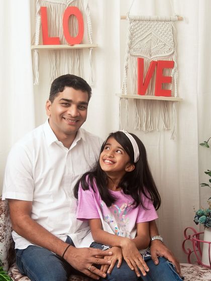 A father and daughter share a look of love and admiration. The 'LOVE' decor in this boho-themed studio setup perfectly complements the feeling in this portrait.