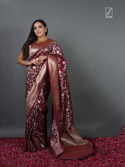 A full-length portrait against a simple grey backdrop, ensuring the traditional saree and the model's elegance are the sole focus.