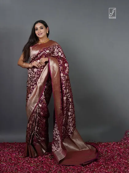 A full-length portrait against a simple grey backdrop, ensuring the traditional saree and the model's elegance are the sole focus.