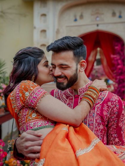 A sweet, candid moment of the couple, with the grand, colorful entrance decor visible in the background.