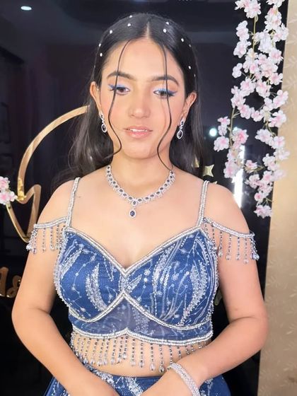 A trendy hairstyle for a younger client, featuring open waves and face-framing tendrils with pearl accents. This is a fresh and modern look for a pre-wedding party.