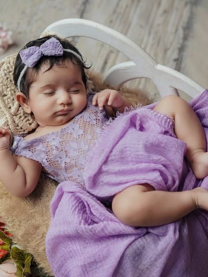 A lavender lullaby. This little one is sleeping peacefully, dressed in a beautiful lace romper in a lovely shade of purple.