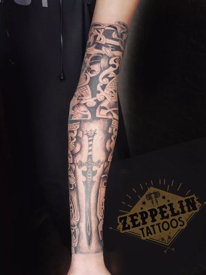 A Viking-inspired sleeve in progress, featuring a sword and intricate Norse knotwork patterns.