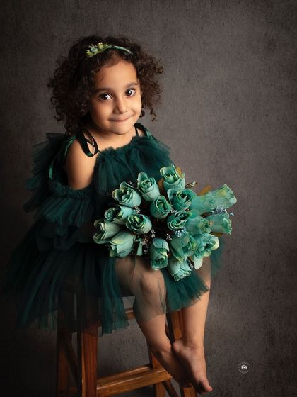 A lovely portrait against a dark background that makes the emerald green dress and her beautiful curly hair stand out.