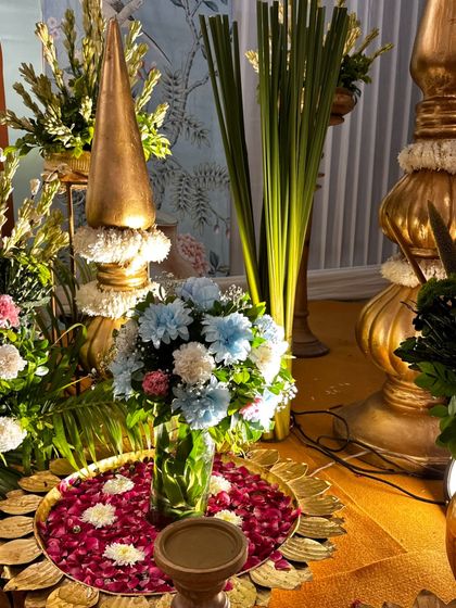 Another shot of the decorative 'urli' and golden 'kalash' style props, surrounded by fresh flowers. These traditional elements are essential for creating an authentic spiritual setting.