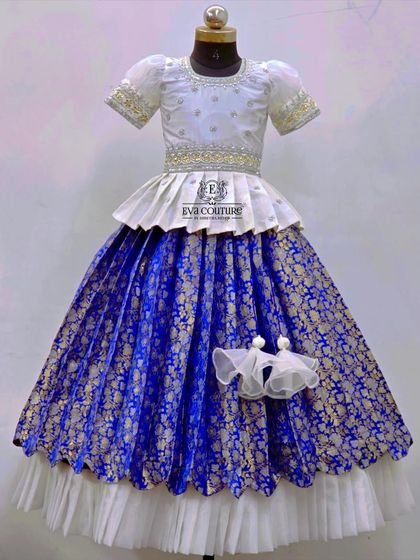 A grand white and royal blue Banarasi lehenga. The white peplum blouse is paired with a rich blue brocade skirt with a double-layered hem.