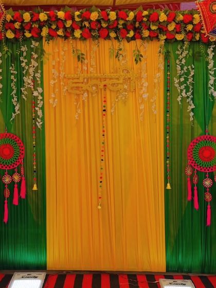 A beautiful Mehandi backdrop with lime green and yellow drapes. The decor features hanging dreamcatchers and floral strings for a delicate and festive look.