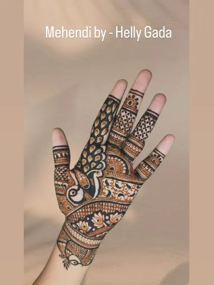 A single hand from a bridal design, showing a peacock with its feathers flowing down the fingers. The use of negative space makes the bird the star of the show.