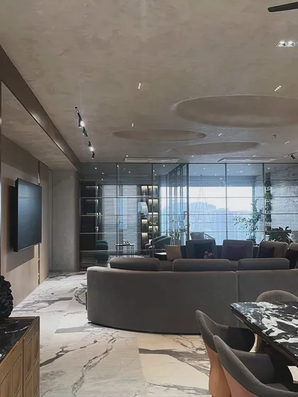 The expansive living area in this modern home is defined by its curved sofa and dramatic marble flooring. The design uses recessed ceiling details and track lighting to create a sense of volume and intimacy.