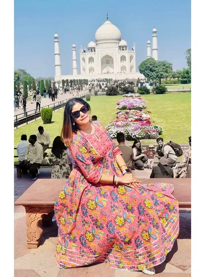 Posing on a bench with the Taj Mahal in the background, this shot showcases my travel outfit and the magnificent monument in one frame.