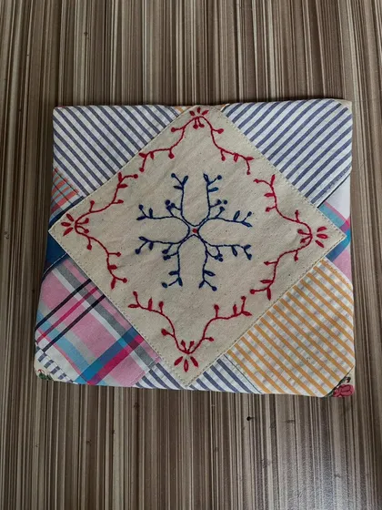 An envelope pouch made from leftover fabric scraps, an example of crazy patchwork. A central hand-embroidered snowflake motif adds a special touch to this repurposed and recycled project.