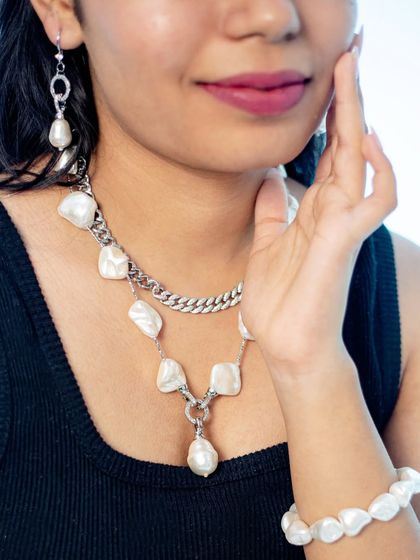 A modern and edgy look featuring a silver chain and baroque pearl necklace. This is for the woman who loves to experiment with her style.