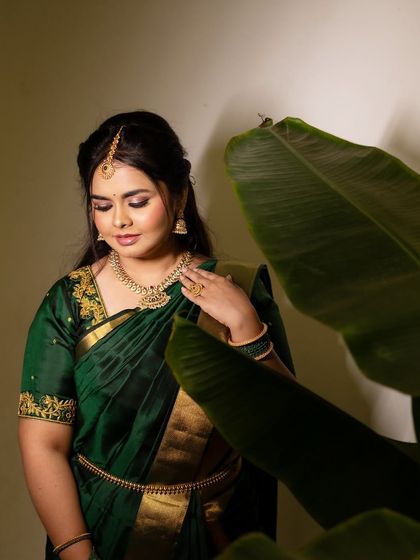 A stunning portrait of Dr. Meghana in a traditional green silk saree for one of her pre-wedding events. The makeup is classic and elegant, with a focus on defined eyes.